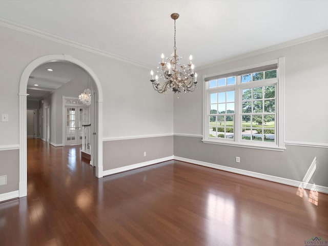 empty room featuring a chandelier, crown molding, and dark wood-type flooring