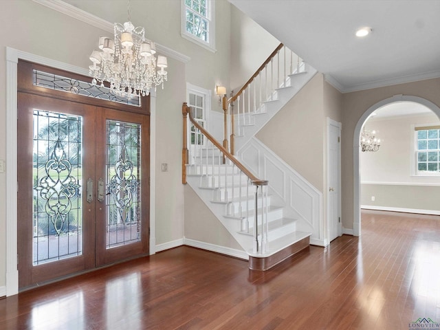 entrance foyer featuring french doors, dark hardwood / wood-style floors, a towering ceiling, a chandelier, and ornamental molding