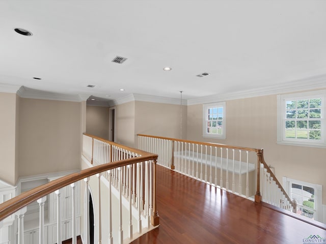 hall with dark hardwood / wood-style floors, a healthy amount of sunlight, and crown molding