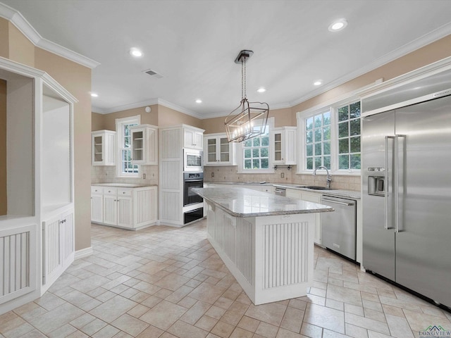 kitchen with pendant lighting, a center island, white cabinets, built in appliances, and decorative backsplash