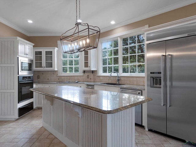 kitchen featuring a kitchen breakfast bar, a kitchen island, sink, built in appliances, and white cabinetry