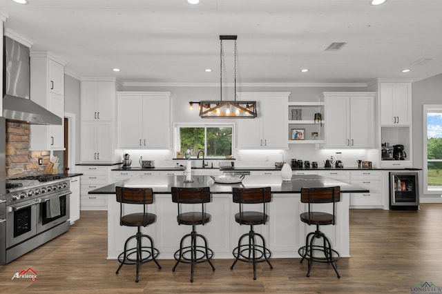 kitchen with a breakfast bar, a center island, double oven range, white cabinetry, and beverage cooler