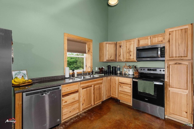 kitchen with appliances with stainless steel finishes, a towering ceiling, light brown cabinetry, and sink