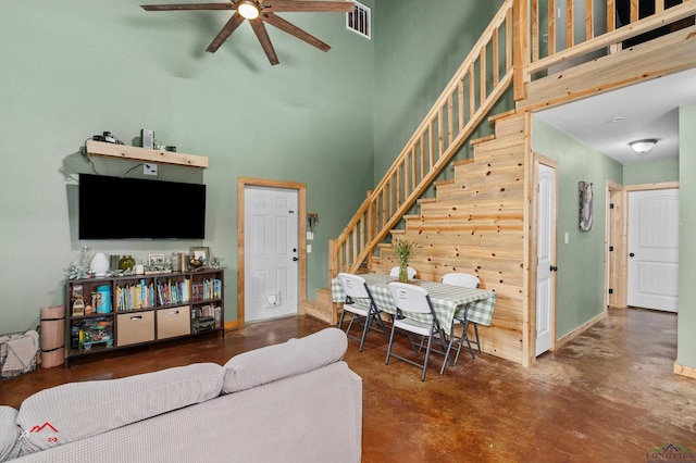 living room featuring concrete flooring, a towering ceiling, and ceiling fan