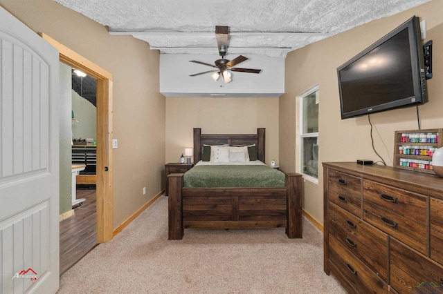 bedroom featuring light carpet, a textured ceiling, and ceiling fan