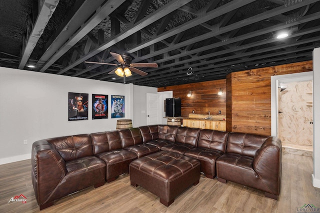 living room with hardwood / wood-style floors, ceiling fan, and wooden walls