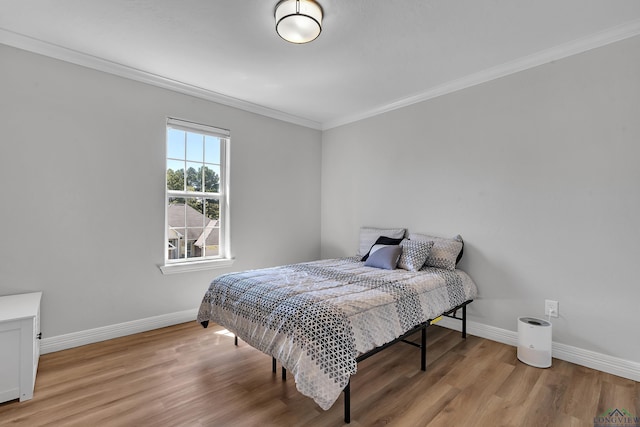 bedroom featuring light wood-type flooring and crown molding