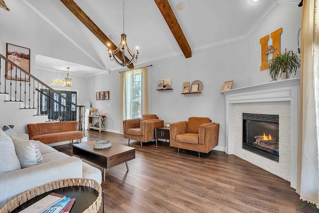 living room featuring hardwood / wood-style floors, high vaulted ceiling, crown molding, a fireplace, and a notable chandelier