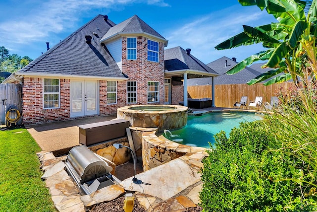 view of pool with pool water feature, a patio area, an in ground hot tub, and french doors