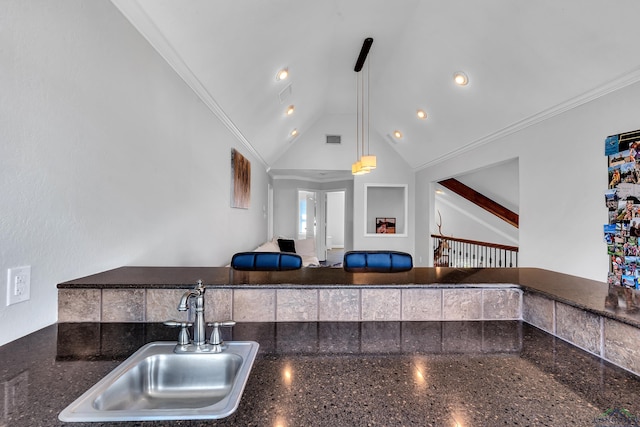 kitchen with lofted ceiling, crown molding, sink, hanging light fixtures, and dark stone countertops