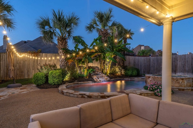 pool at dusk with a patio area and pool water feature