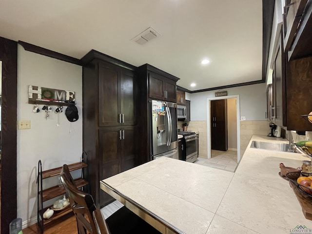 209 Lake Lamond Rd, Longview, TX 75604 - kitchen with appliances with stainless steel finishes, recessed lighting, crown molding, dark brown cabinetry, and light tile patterned floors
