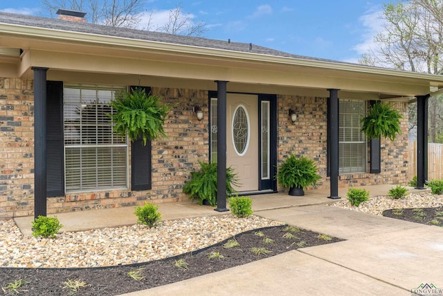 view of exterior entry with brick siding and covered porch