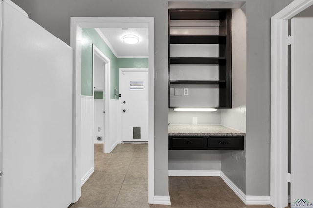 hallway featuring crown molding, tile patterned floors, and baseboards