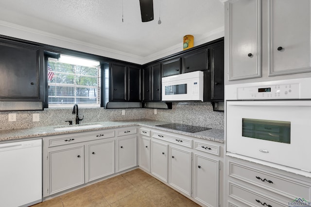 kitchen with tasteful backsplash, a sink, dark cabinetry, white appliances, and light tile patterned flooring