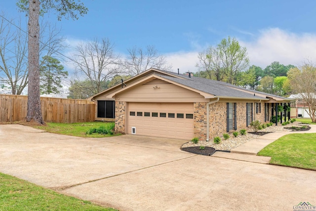view of front of home with fence, concrete driveway, brick siding, and a garage