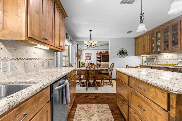 8 Honeysuckle Ln, Longview, TX 75605 - kitchen featuring stainless steel dishwasher, dark wood-type flooring, brown cabinetry, a chandelier, and decorative backsplash