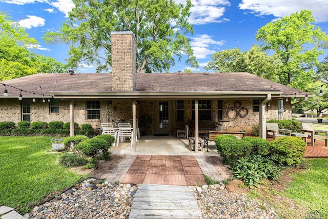 8 Honeysuckle Ln, Longview, TX 75605 - rear view of house with a chimney, a lawn, a patio, and brick siding