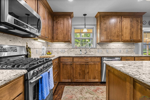 8 Honeysuckle Ln, Longview, TX 75605 - kitchen featuring stainless steel appliances, a sink, wood finished floors, light stone counters, and brown cabinets