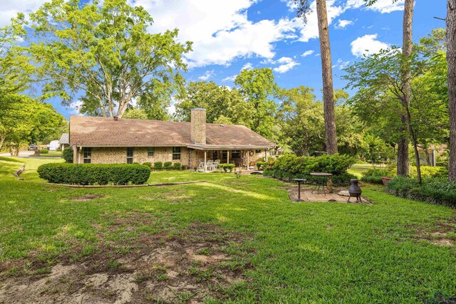 8 Honeysuckle Ln, Longview, TX 75605 - back of house with a yard, a chimney, a patio area, and view of wooded area
