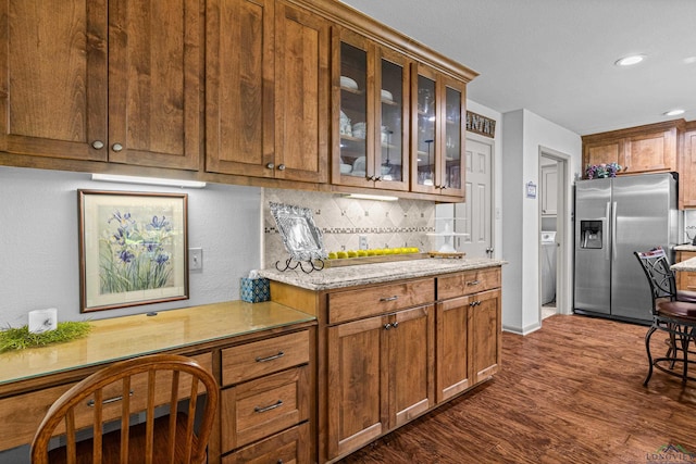 8 Honeysuckle Ln, Longview, TX 75605 - kitchen featuring stainless steel fridge, tasteful backsplash, glass insert cabinets, dark wood finished floors, and brown cabinetry