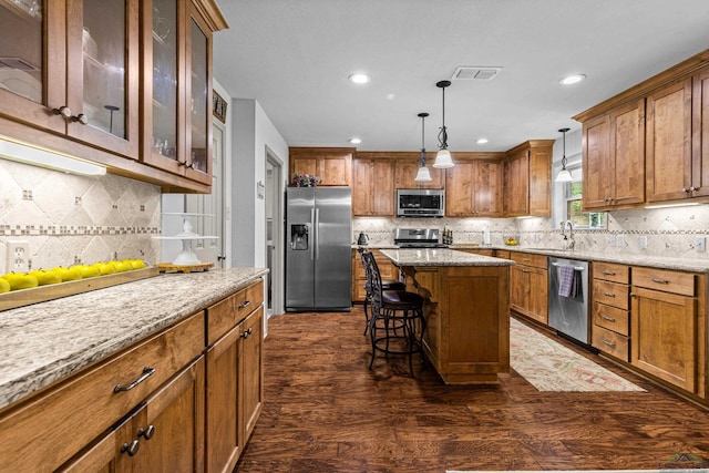 8 Honeysuckle Ln, Longview, TX 75605 - kitchen with stainless steel appliances, brown cabinets, backsplash, a breakfast bar area, and recessed lighting