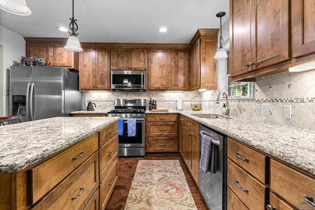 8 Honeysuckle Ln, Longview, TX 75605 - kitchen featuring stainless steel appliances, a sink, dark wood finished floors, brown cabinets, and light stone counters