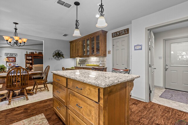 8 Honeysuckle Ln, Longview, TX 75605 - kitchen with a chandelier, a center island, glass insert cabinets, light stone countertops, and backsplash