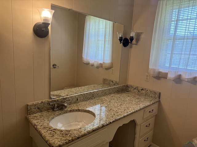 bathroom featuring a decorative wall, plenty of natural light, and vanity