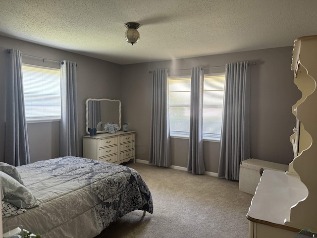 bedroom with a textured ceiling, light colored carpet, multiple windows, and baseboards