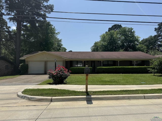 ranch-style home featuring a garage, a front lawn, and aphalt driveway