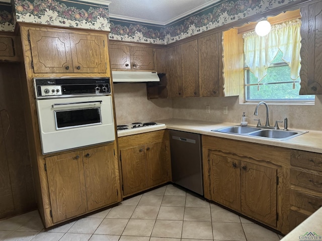 kitchen featuring a sink, light countertops, brown cabinets, and white appliances