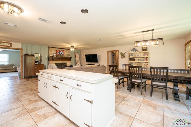 12545 Fm 968 W, Longview, TX 75602 - kitchen with ceiling fan, a brick fireplace, a kitchen island, and light tile patterned floors