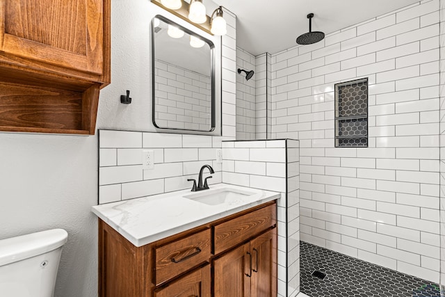 full bathroom featuring tiled shower, backsplash, toilet, and vanity