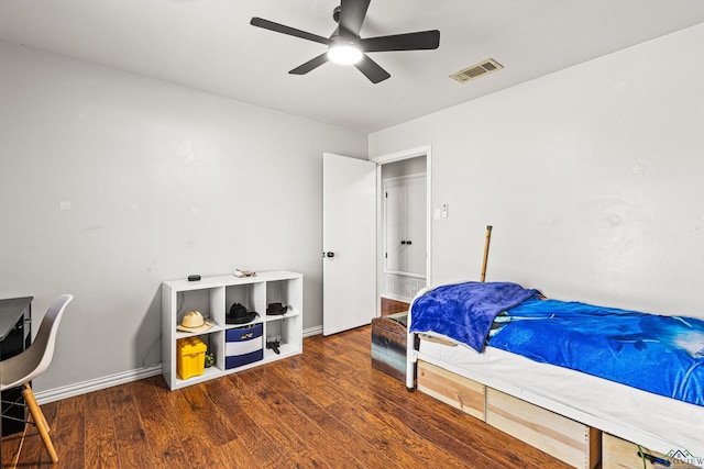 bedroom with a ceiling fan, visible vents, baseboards, and wood finished floors