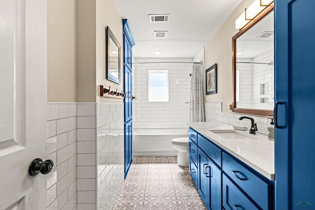 bathroom with toilet, visible vents, vanity, tile walls, and tile patterned floors