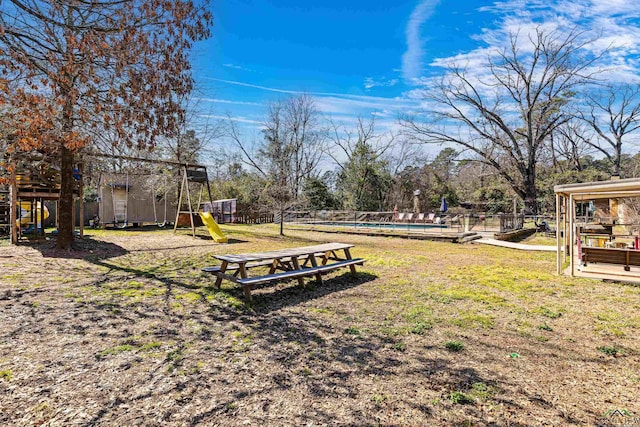 view of yard with a pool, fence, and playground community