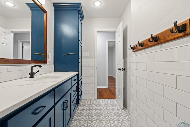 bathroom featuring vanity, a wainscoted wall, tile patterned flooring, and tile walls