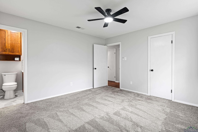 unfurnished bedroom featuring carpet flooring, visible vents, baseboards, a ceiling fan, and ensuite bath