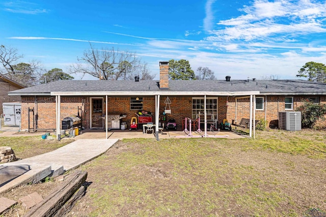 rear view of property with a patio, brick siding, a chimney, and cooling unit