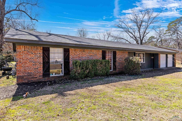 ranch-style house featuring an attached garage, a front lawn, and brick siding