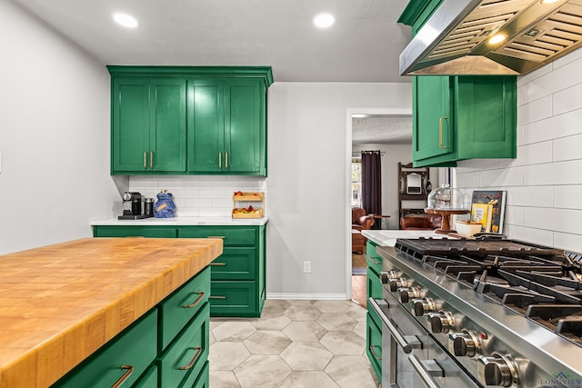 kitchen with tasteful backsplash, green cabinetry, wall chimney range hood, and high end stainless steel range