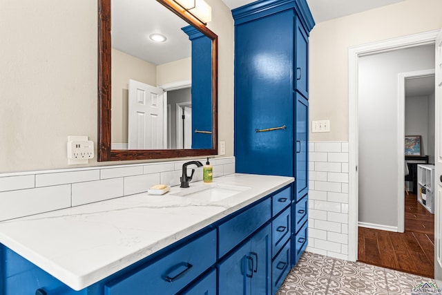 bathroom featuring wainscoting, tile walls, vanity, and wood finished floors