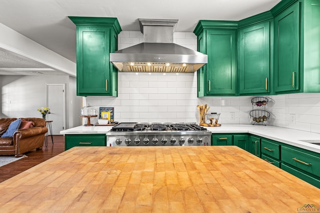 kitchen featuring wall chimney exhaust hood, butcher block countertops, decorative backsplash, and green cabinetry