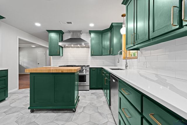 kitchen featuring a sink, green cabinets, wall chimney range hood, and stainless steel appliances