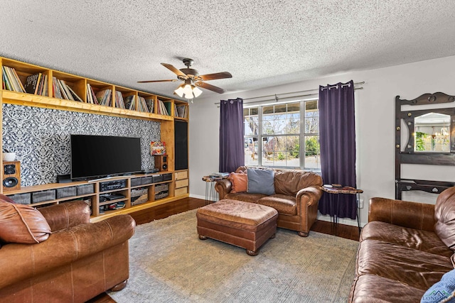 living area with a ceiling fan, a textured ceiling, baseboards, and wood finished floors