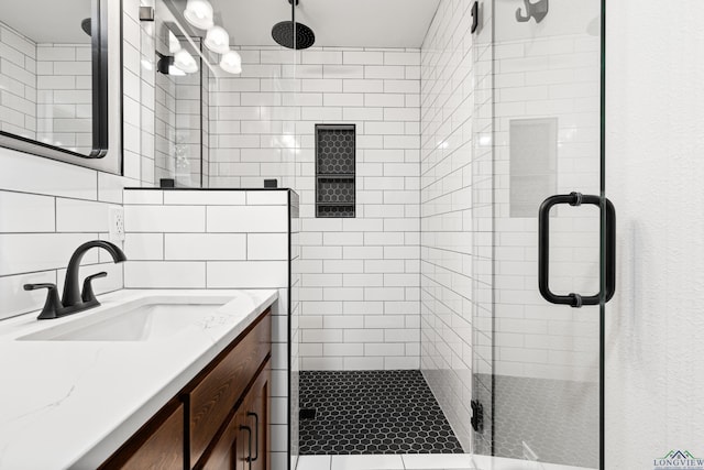 bathroom with tile walls, a shower stall, and vanity