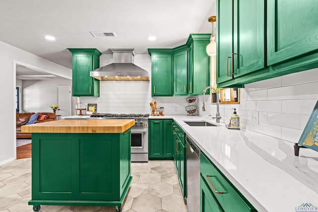 kitchen featuring a sink, wooden counters, wall chimney range hood, appliances with stainless steel finishes, and green cabinetry