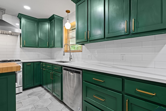 kitchen featuring tasteful backsplash, a sink, appliances with stainless steel finishes, green cabinets, and wall chimney exhaust hood