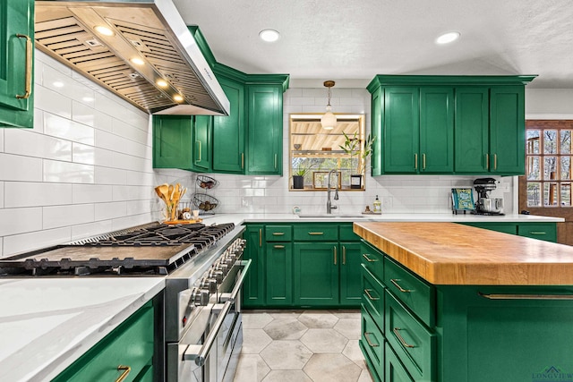 kitchen featuring range with two ovens, green cabinetry, a sink, and wall chimney range hood